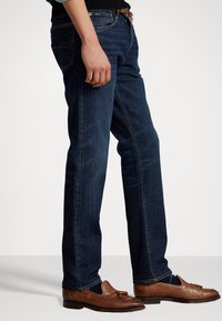 Mörka denimjeans med rak passform. Har kontrasterande sömnad, fem fickor och en sliten textur. Matchas med bruna läderskor.