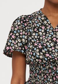 Abito floreale con maniche corte a sbuffo, sfondo nero, presenta fiori pastello in rosa e blu, e una vita arricciata per un look aderente.