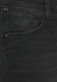 Zwarte denim jeans met een soepele textuur, voorzien van een klein merklabel, een voorzak en contrasterende stiksels.