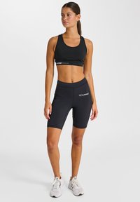 Sort sports-bh og matchende cykelshorts med høj talje i stretchstof. Har logodetaljer og en tætsiddende pasform til atletisk brug.