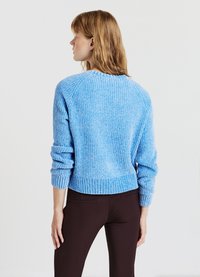 Helles blaues gestricktes Sweatshirt mit gerippter Textur, Raglanärmeln und einem cropped Schnitt. Mit Rundhalsausschnitt und breiten Bündchen.