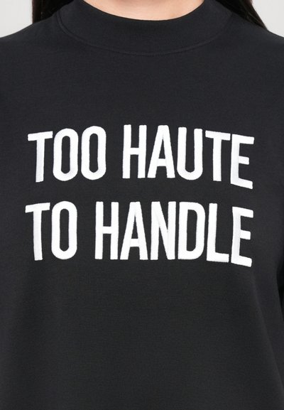 Musta sweatshirt, millel on julge valge tekst "TOO HAUTE TO HANDLE." Lihtne disain klassikalise ümmarguse kaeluse kujuga. Pehme tekstuur.