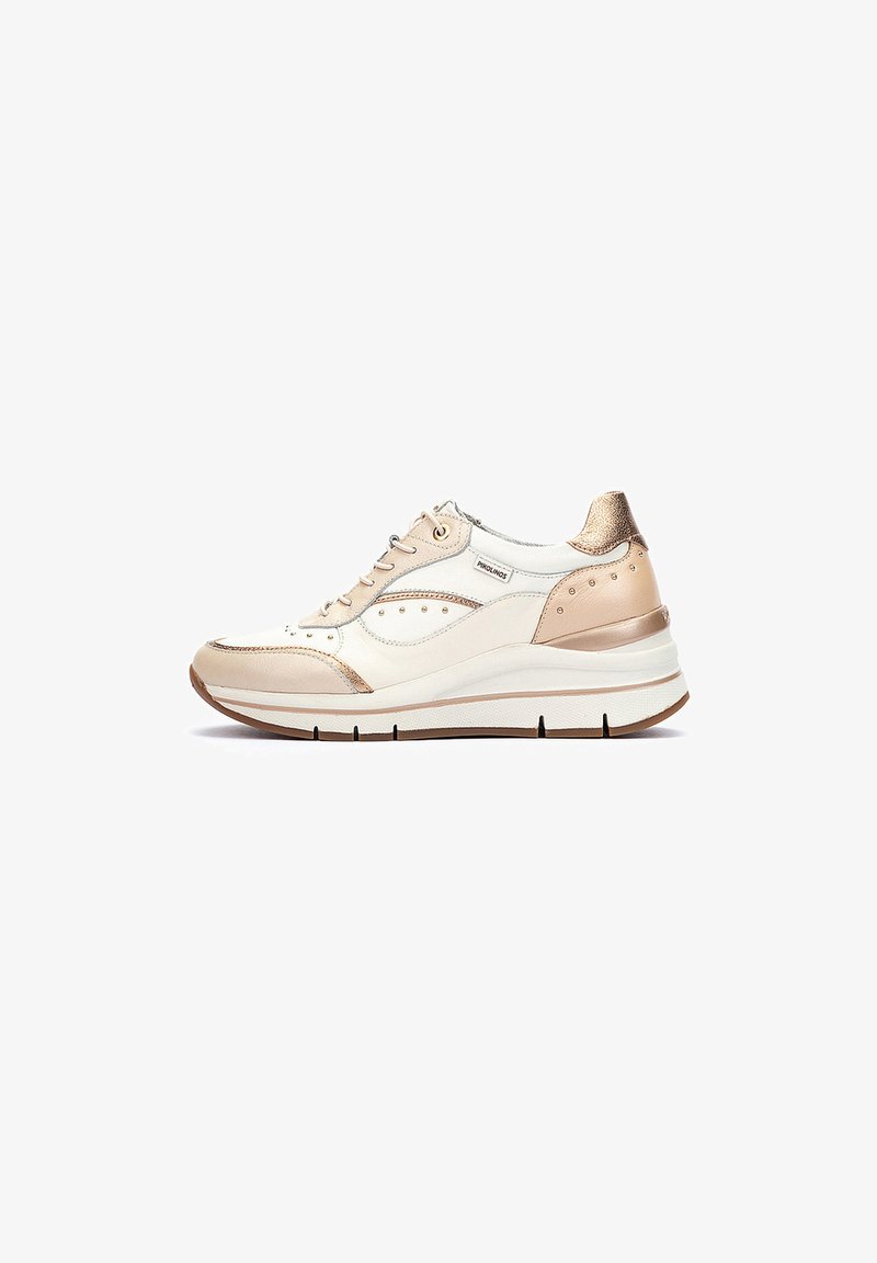 Baskets sportives avec une tige en cuir crème et beige, des accents métalliques dorés, des détails perforés et une semelle blanche épaisse.