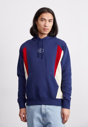 Navy hoodie with a front pocket, featuring red and cream side panels and a logo on the chest. Constructed from cotton blend fabric.