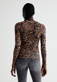 Long-sleeve top in leopard print, featuring a fitted design, soft texture, and a round neckline. Color palette includes brown and black.