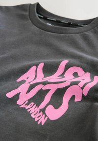 Grå T-shirt med et stort, legende pink grafisk tekstdesign, der læser "ALL SAINTS LONDON." Lavet af blødt stof med rund halsudskæring.