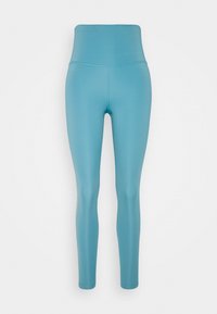 Vysoké legíny v světle modré látce, hladká textura, přiléhavý střih, elastický materiál, kontrastní švy podél stran.