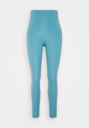 Hoch geschnittene Leggings aus leicht blauem Stoff, glatte Textur, enganliegendes Design, dehnbarem Material, kontrastierende Nähte entlang der Seiten.