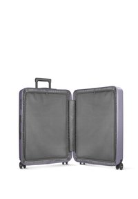 Valise rigide violette, ouverte pour révéler un intérieur gris avec des poches en mesh. Comprend une poignée rétractable et des roues lisses.