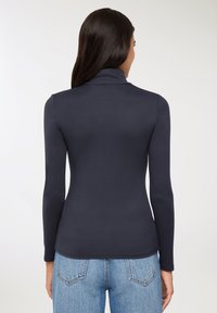 Granatowa bluzka z długim rękawem i stójką, wykonana z gładkiego, elastycznego materiału. Posiada dopasowany krój i bezszwowy design z tyłu.