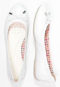 Vita balettskor med rundad tå, tygrosett och silverdetaljer. Det inre fodret har ett färgglatt prickigt mönster. Slät textur.