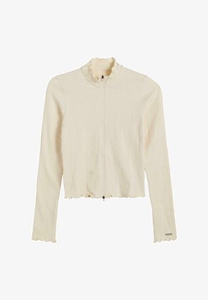 Giacca zip-up colore crema, a coste, con colletto e orlo arricciati. Presenta maniche lunghe e una vestibilità aderente. La chiusura è zip.