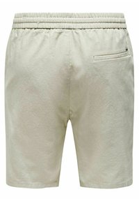 Shorts bej din material ușor, cu talie elastică, buzunar lateral și textură netedă. Lungime scurtă.