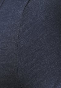 Navy blue fabric showing a textured surface with fine ribbing; includes smooth portions and seam detailing, indicating a fitted design.