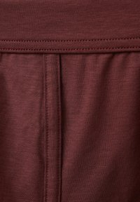 Burgundowa tkanina o gładkiej strukturze z szerokim pasem w talii i centralnym szwem, prezentująca rozciągliwy, casualowy fason.