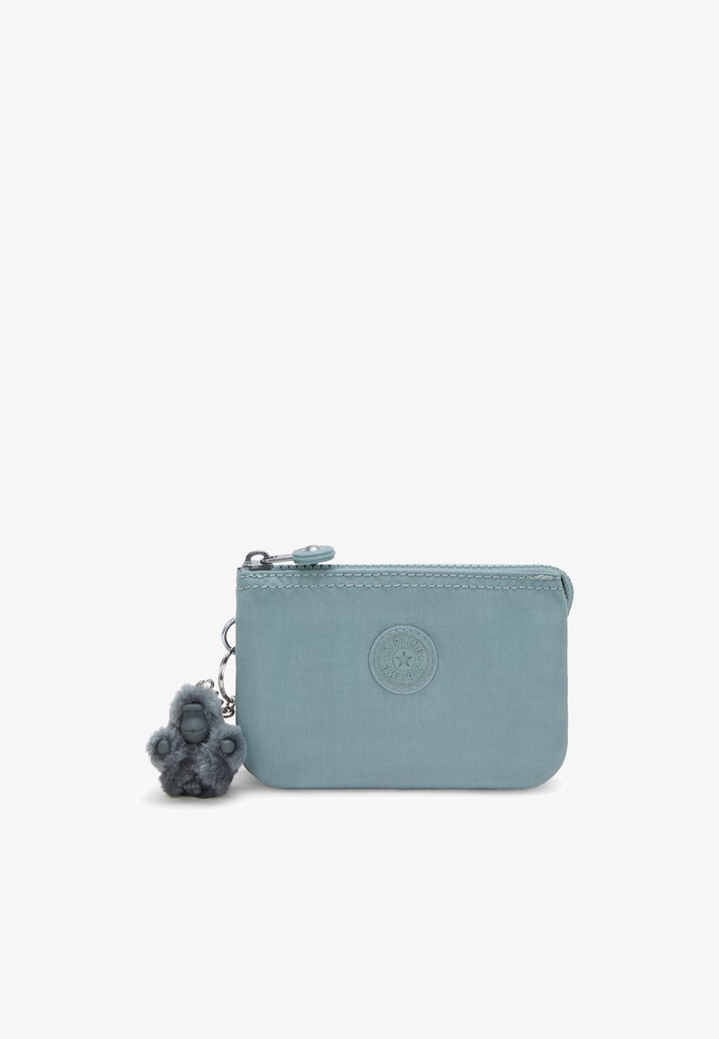 Light blue zippered pouch made of smooth fabric. Features a round embossed logo and a gray fuzzy keychain accent. Compact and rectangular shape.