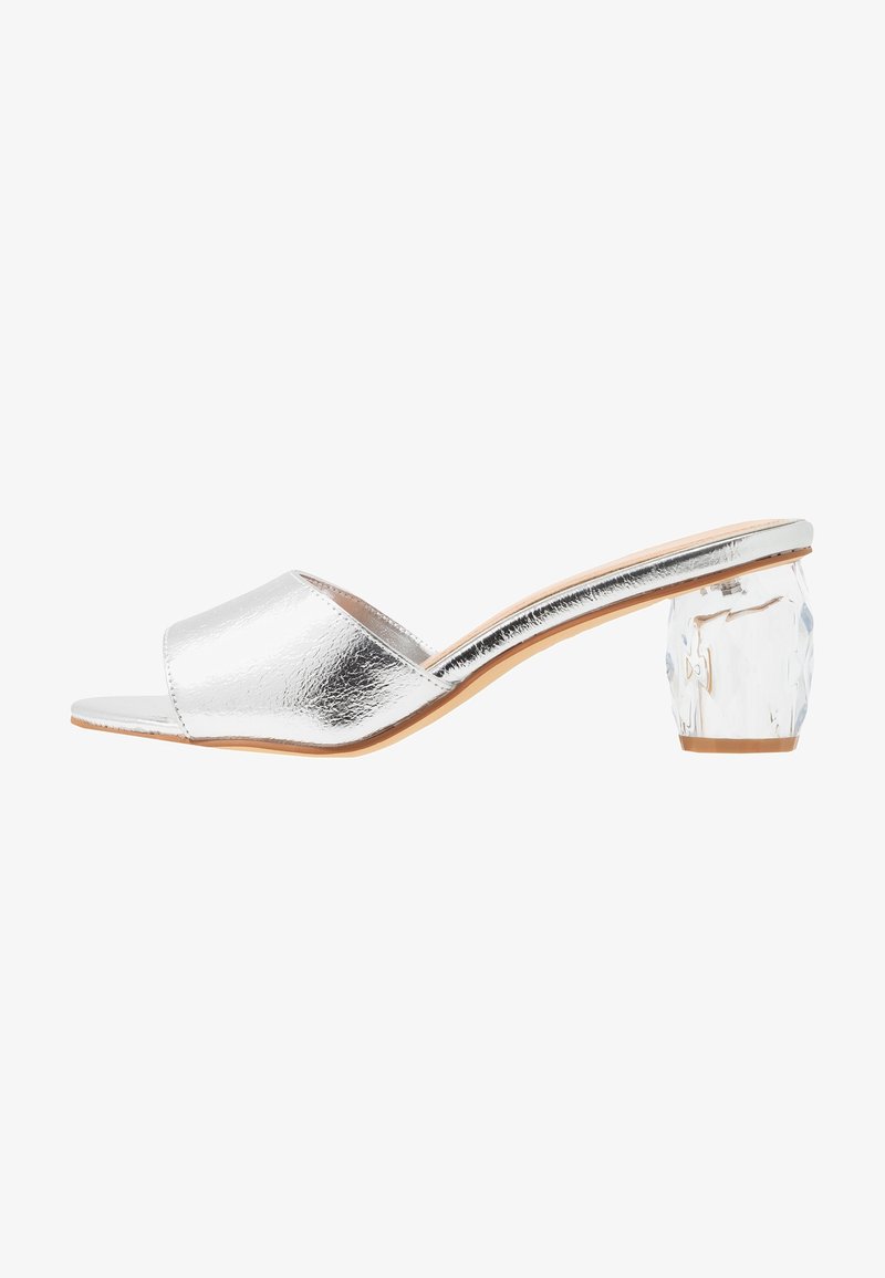 Sandale à talon métallique argenté avec un bout ouvert, texture lisse et un talon en bloc sculpté et transparent. Conception élégante avec une silhouette minimaliste.