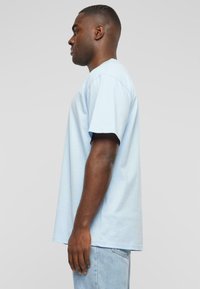 Light blue cotton t-shirt with short sleeves, crew neckline, and a relaxed fit. Plain design, no patterns or accents visible.