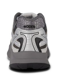 Grå sportskor med en texturerad ovansida, silverdetaljer, mesh-inklädnad och en svart sula. Har varumärket "WODEN" på hälen.