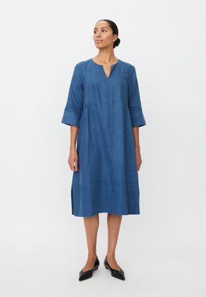 Niebieska lniana sukienka z rękawami do połowy przedramienia, dekoltem w serek, talią marszczoną, bocznymi rozcięciami oraz luźnym fasonem sięgającym poniżej kolan.