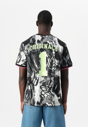 Schwarz-weiß gemustertes Kurzarm-Trikot mit grüner "ORIGINALS"-Aufschrift und der Nummer "1" auf der Rückseite. Verfügt über rosa Akzente an den Ärmeln.