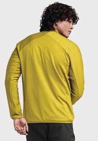 Gelbes, langärmeliges Sportoberteil mit gerippter Textur, hohem Kragen und kontrastierenden Nähten. Leichter Stoff, geeignet für Sportbekleidung.