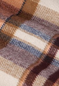 Wollen deken met een ruitpatroon in tinten bruin, crème en blauw, met een zachte textuur en warme kleurcombinaties.