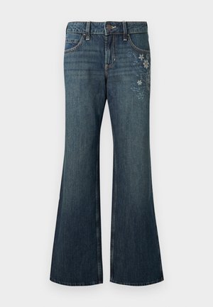 Tumesinised laienevate säärega teksad ees oleva nööbi, taskute ja helede lillemustriliste tikanditega paremal reiel, ühtlasel taustal.