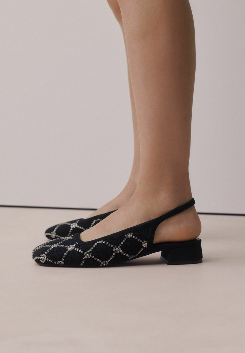 Sorte slingback sko med tekstureret stof, udsmykket med sølvfarvede rhinsten i et diamantmønster, og en lav firkantet hæl.