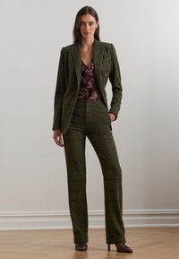 Groen geruite pak met een dubbelgeknoopte blazer en op maat gemaakte broek. Draag het met een bloemenbloes, aangevuld met bruine hoge hakken.