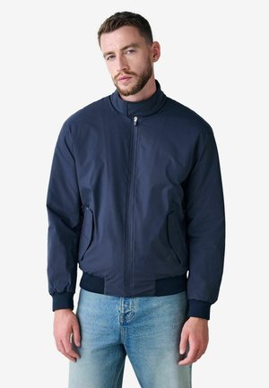 Navy bomber jacket with a high collar, front zipper, side pockets, ribbed cuffs, and hem. Made from lightweight, smooth fabric.