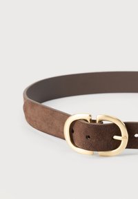 Brązowy zamszowy pasek z okrągłą złotą klamrą i wieloma otworami do regulacji rozmiaru. Gładka tekstura i elegancki design.