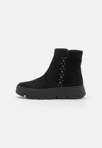 Bottines en suède noir avec une semelle épaisse noire et des accents décoratifs en perles sur le côté. Texture lisse et design ajusté.