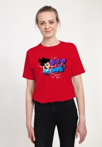Rød bomulds T-shirt med en tegneserie-grafik og teksten "Skating and Work!" i lilla og blå, sat imod en sprøjtet baggrund.