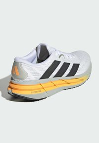 Lightweight white athletic shoe with black stripes, gray and yellow sole, textured upper, and padded collar. Features "REPETITOR" branding.