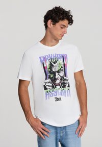 Biała bawełniana koszulka z grafiką przedstawiającą Jokera oraz napisem "Arkham Asylum". Design zawiera żywe kolory i tekstury.