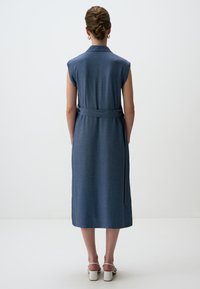 �Ärmelloses blaues Kleid mit einem taillierten Gürtel, Knopfkraagen und knielangem Saum. Hergestellt aus strukturierter Stoff, mit seitlichen Taschen.
