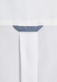 Weißer Stoff mit glatter Textur, an der Oberseite mit einem blauen Denim-Element akzentuiert. Enthält eine vertikale Naht für designtechnische Details.