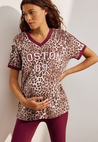 T-shirt med leopardmönster i brunt och krämvitt, med vinröd V-ringning och ärmslut, med texten "BOSTON 89" tryckt i vitt.