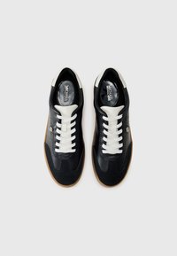 Zwarte leren en suède sneakers met witte veters, een zool van gumrubber en witte accenten op de hak. Ronde neus en geperforeerd ontwerpdetail.