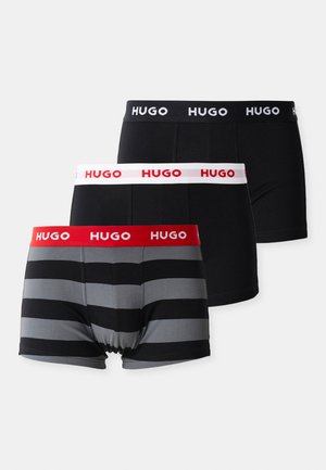 Drei Paar Herren-Boxershorts: eine einfarbig schwarze, eine einfarbig graue mit schwarzen Streifen und eine schwarze mit einem weißen Bund und roten Buchstaben.