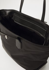 Black tote bag with smooth exterior, two shoulder straps, and a zippered interior pocket. The material is durable and water-resistant.