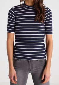 Niebiesko-biała bluzka z krótkim rękawem w paski, z wysokim dekoltem, wykonana z elastycznego materiału, ściśle przylegająca do ciała.