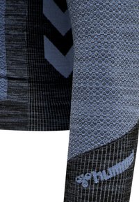 Camiseta deportiva de manga larga con un patrón texturizado en azul y negro, que presenta un diseño de panal y un logotipo destacado de la marca en la parte inferior de la manga.