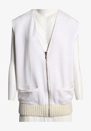 Chaleco blanco sin mangas con cremallera, dos bolsillos delanteros y un dobladillo de punto acanalado, exhibido en un maniquí.