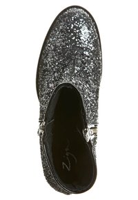 Bottine noire recouverte de paillettes argentées avec des zips sur le côté et un bout arrondi, vue de dessus.