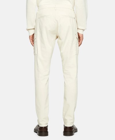 Pantaloni cargo bianchi a vestibilità dritta con tasche laterali, passanti per cintura e una texture liscia; indossati con scarpe marroni scure.