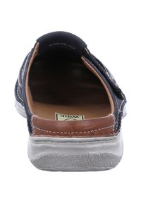 Navy slip-on shoe with brown leather accents, white stitching, and a textured sole. Interior features a cushioned brown footbed.