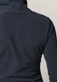 Sudadera con capucha de vellón de color azul marino oscuro, con una textura suave, que presenta un cuello alto y costuras finamente cosidas, diseñada para proporcionar calidez y comodidad.