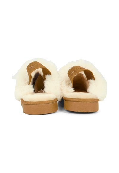 Paire de chaussons ouverts couleur fauve avec une doublure épaisse en fausse fourrure blanche et des larges sangles élastiques, vue de dos sur fond blanc.